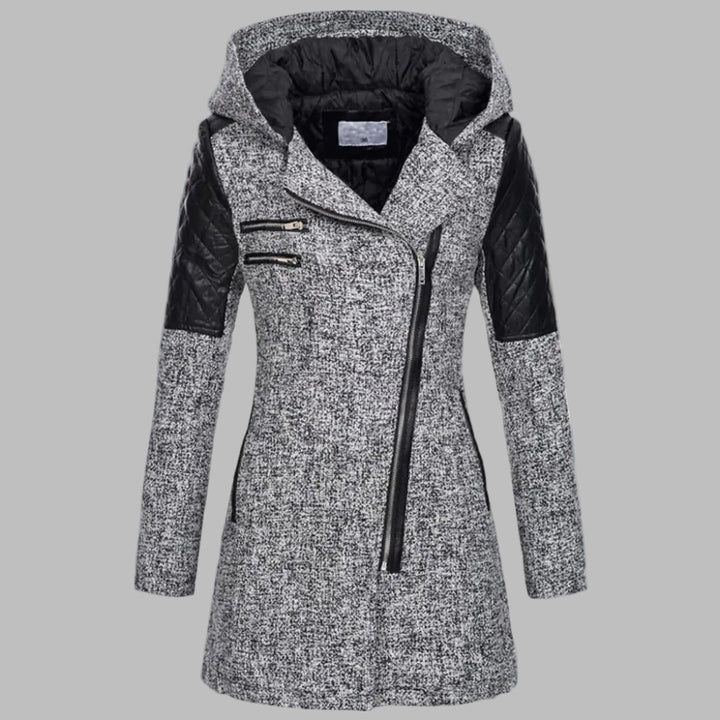 Grijze dames winterjas met capuchon, asymmetrische ritssluiting en zwarte leren accenten, ideaal voor koude weersomstandigheden en modieuze winterstijl.